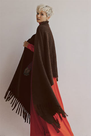 フリンジニットストール 39,600円／アソース メレ、タートルネックニットワンピース 49,500円／knit bar（ともにアイネックス）　鮮やかなオレンジに深みと落ち着きをもたらす、ブラウンに近い赤みがかったグレーカラー。アルパカ毛にウールをまぜた保温性の高い素材を、空気感を含むループ状の糸に仕立てることで、重厚な見た目に反してライトな着心地。