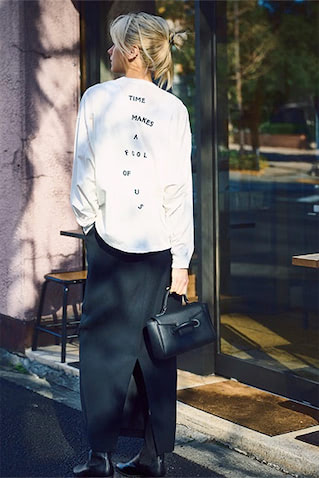 サテン風の黒スカートが、 ゆるいロンＴにキレと女っぽさをカバー： 黒スカート 40,700円／THE NEWHOUSE（アーク インク）　白ロングスリーブTシャツ 16,500円／HAKUJI（ブランドニュース）　黒ハンドバッグ 44,000円／VASIC（ヴァジックジャパン）　黒サイドゴアブーツ 29,700円／DIANA（ダイアナ 銀座本店）　ツヤ＆とろみをそなえたドレスライクな風合いは、なびかない形で冷静に。キャッチーなロゴＴも、大人の遊び心にとどめてくれる。