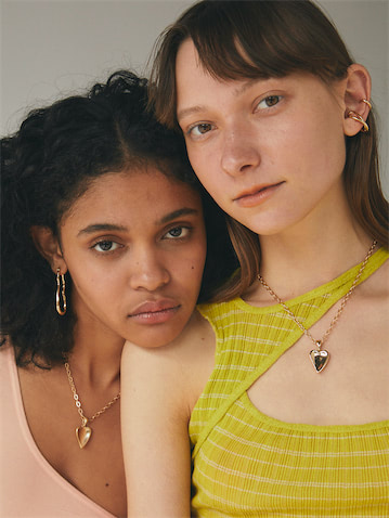 (右)CURVED CROSS EAR CUFF / GOLD 2,090円(税込み)、MATURE HEART NECKLACE / GOLD 2,090円(税込み）(左)CURVY LINE PIERCE / GOLD 1,870円(税込み)、MATURE HEART NECKLACE / MATTE GOLD 2,090円(税込み)