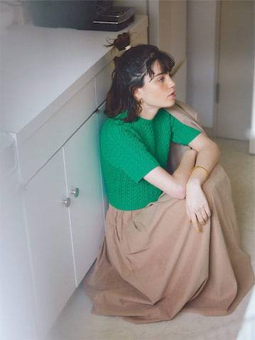 ベージュリネンジャケット 25,300円／TODAYFUL（Life’s 代官山店）　ベージュサスペンダーつきロングスカート 17,600円／JILKY　フラットフープピアス 3,850円／CREDONA　バングル 50,600円／GARNI（ガルニトウキョウ）　グリーンケーブルニット 16,500円／MACPHEE（TOMORROWLAND）　目のつまったコンパクトな短め丈。厚みのあるケーブルながら着心地はさらっとしたコットン素材。