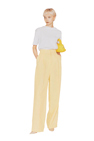 見慣れたスラックスを 「そのままに」色だけ変更：●イエローツイルパンツ 14,300円／uncrave STANDARD（uncrave）　白Tシャツ 8,580円／リフィル（リフィル カスタマーサービス）　バッグ 73,700円／マーレット（サザビーリーグ）　パンプス 35,200円／PIPPICHIC（ベイジュ）■彩度はひかえめで、肌なじみもいい。まるでベージュパンツのような立ち振る舞いをする、あせたネオンのような発色。なめらかな質感が、色の印象をよりマイルドに見せてくれる。
