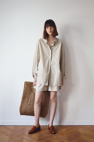 【パジャマ風シャツとショートパンツ】ショートパンツをおおうように、大きなシャツをバサッと重ねる心地よさ。部屋着っぽく見えない理由はわずかに光沢を含んだ、実はドレッシーな風合いだから。●ベージュストライプシャツ 57,200円、ショートパンツ 34,100円／ともにスタジオ ニコルソン（インコントロ）　　ラフィアバッグ 14,300円／MADE IN MADA（ジャック・オブ・オール・トレーズ プレスルーム）　ローファー 16,390円／A de Vivre　無造作な着くずしに大きなかごバッグ。