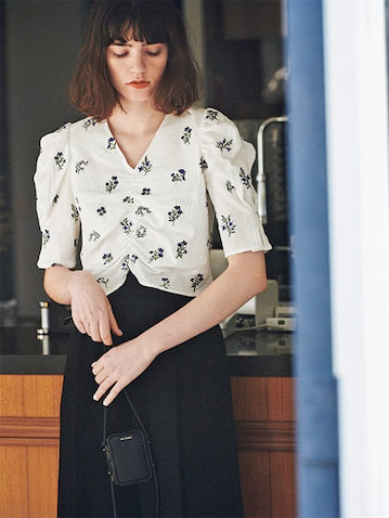 細身＆シャープなVネックで花柄をスマートに ⚫︎白フラワーエンブロイダリーブラウス 9,350円／MOUSSY（バロックジャパンリミテッド）　黒オックスフォードパンツ 42,900円／ATON（ATON AOYAMA）　黒ショルダーポーチ 72,600円／LUTZ MORRIS（エスケーパーズオンライン）　ヴィンテージライクな花柄がほっこりせずにモダンに傾く切れ味を意識。
