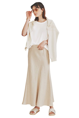 白ノースリTシャツ 12,100円／ATON（ATON AOYAMA）　肩がけした白ニット 59,400円／BODHI（alpha PR）　ベージュリネンスカート 23,100円／プルミエ アロンディスモン　サングラス 20,900円／ロンハーマン バングル 50,600円／ガルニ（ガルニトウキョウ）　サンダル 27,500円／FABIO RUSCONI（エリオポール代官山）　白っぽい配色の中では濃度がある、ベージュのボトムを選び、白トップスのレイヤードを締めて。