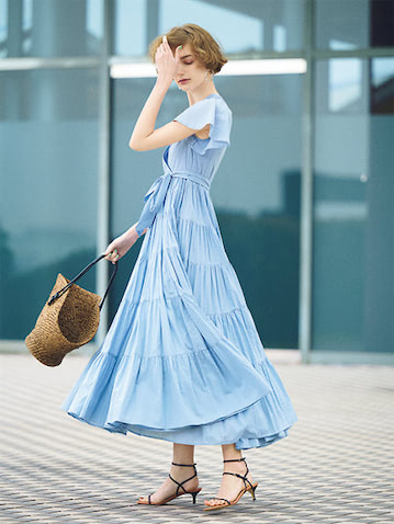 すそもそでもとことん甘いデザインは 清涼なブルーで大人のフェミニンへと昇華：● ライトブルーティアードワンピース 35,200円／MARIHA（ショールーム セッション）　クリアピアス 30,800円／Lemme.　かごバッグ 26,400円／マルシェ（フラッパーズ）　サンダル 121,000円／フランチェスコ ルッソ（ロンハーマン）　■ほんのり透ける、エアリーなコットン素材を使ったカシュクールワンピース。ティアード部分は生地が二重になっているため、想像以上にボリューミィな動きを生み華やかな姿に。