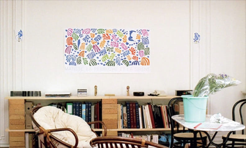 絵を生かすための真っ白な壁 「アンリ・マティスの絵画が飾ってあるのが印象的。無造作に置かれたバケツやサイドボードの上に陳列されたものなど全体的に物が多いですが、白を基調とした部屋だからかすっきりとして見える。絵画の左右にはポストカードをはっているのもステキです」（苅田さん） ⚫︎『春のソナタ』（1989）